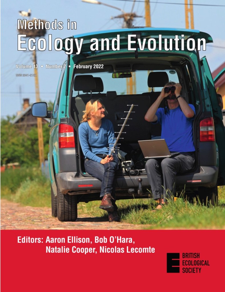 The MEE February journal cover, showing two researchers, one holding binoculars and the other a satellite antenna. There is a stork in a nest behind them.